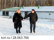 Счастливая семья. Весёлые мужчина и женщина среднего возраста взявшись за руки бегут по зимней дороге (2018 год). Редакционное фото, фотограф Игорь Низов / Фотобанк Лори