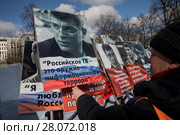 Мужчина берет плакат с портретом Бориса Немцова во время марша по бульварам города Москвы в третью годовщину с момента убийства политика Бориса Немцова, Россия, 25 февраль 2018. Редакционное фото, фотограф Николай Винокуров / Фотобанк Лори