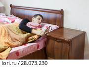 Проснувшийся в кровати мужчина смотрит на часы на тумбочке. Стоковое фото, фотограф Кекяляйнен Андрей / Фотобанк Лори