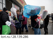 Мужчины несут купленные на Рижском цветочном рынке букеты цветов в канун Международного женского дня - 8 марта в городе Москве, Россия (2018 год). Редакционное фото, фотограф Николай Винокуров / Фотобанк Лори