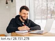 A freelancer with a laptop writes a note in a notebook. Стоковое фото, фотограф Виктор Аллин / Фотобанк Лори