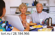 Young woman showing elderly couple something interesting on laptop over cup of tea. Стоковое видео, видеограф Яков Филимонов / Фотобанк Лори