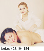 Female massage master is doing healty massage of back and loin to adult woman. Стоковое фото, фотограф Яков Филимонов / Фотобанк Лори