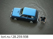 Незадачливый водитель и его пассажир оказались в водной ловушке на полностью затопленной улице. Город Петрозаводск (2016 год). Редакционное фото, фотограф Сергей Цепек / Фотобанк Лори