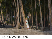 Young beautiful woman standing in a tropical forest leaning on a palm tree. Стоковое фото, фотограф Некрасов Андрей / Фотобанк Лори