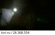 Young explorers in helmets with flashlights scrambles on all fours in the dark cave. Стоковое видео, видеограф Константин Шишкин / Фотобанк Лори