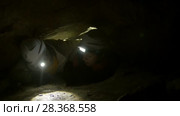 Two young hikers explorers stuck in the narrow hole in dark cave. Стоковое видео, видеограф Константин Шишкин / Фотобанк Лори