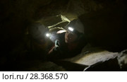 Two young hikers explorers stuck in the narrow hole in dark cave. Стоковое видео, видеограф Константин Шишкин / Фотобанк Лори
