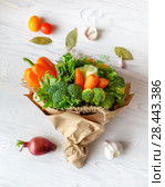 Bouquet of fresh vegetables lies on a white wooden table. Nearby is a red onion, tomatoes, garlic, bay leaf. View from above. Стоковое фото, фотограф Олег Белов / Фотобанк Лори
