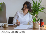 Woman writing at office during working day. Стоковое фото, агентство Ingram Publishing / Фотобанк Лори