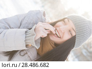 Young woman in winter outfit eats a biscuit lit by sunshine. Стоковое фото, фотограф Kirill Kedrinskiy / Ingram Publishing / Фотобанк Лори