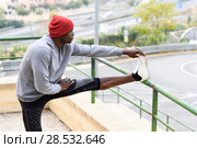 Black man doing stretching before running outdoors. Young male exercising with city scape at the background. Стоковое фото, фотограф Javier Sánchez Mingorance / Ingram Publishing / Фотобанк Лори