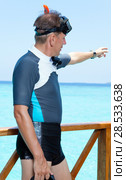 Sports man in equipment for a snorkeling on sundeck shows a hand in the sea. Maldives. Стоковое фото, фотограф Куликов Константин / Фотобанк Лори