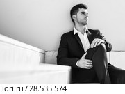 Young businessman near a modern office building wearing black suit and white shirt sitting on the floor. Man with blue eyes in urban background. Стоковое фото, фотограф Javier Sánchez Mingorance / Ingram Publishing / Фотобанк Лори