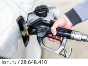 Closeup of mans hand pumping gasoline fuel in car at gas station. Стоковое фото, фотограф Matej Kastelic / Фотобанк Лори