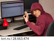 Интернет тролль у компьютера. Неприятный молодой человек пишет вредные комментарии в сети и показывает жест "ОК" Стоковое фото, фотограф Лариса Капусткина / Фотобанк Лори