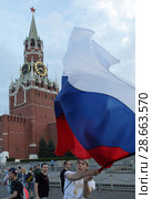 Болельщик Российской сборной с флагом страны на фоне Кремлевских курантов (2018 год). Редакционное фото, фотограф Дмитрий Неумоин / Фотобанк Лори