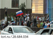 Болельщики сборной России после матча Россия-Испания размахивают флагами из автомобиля на Лубянке (2018 год). Редакционное фото, фотограф Дмитрий Неумоин / Фотобанк Лори
