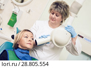 dentist operates dental intraoral x-ray unit for tooth image with patient. Стоковое фото, фотограф Дмитрий Калиновский / Фотобанк Лори