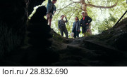 Group of happy friends explorers standing at the entrance of the cave in forest. Стоковое видео, видеограф Константин Шишкин / Фотобанк Лори