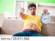 Man suffering from extra kilos in time management concept. Стоковое фото, фотограф Elnur / Фотобанк Лори