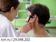 Female doctor checking patient's ear during medical examination. Стоковое фото, фотограф Elnur / Фотобанк Лори