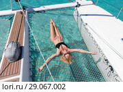 Woman relaxing on a summer sailing cruise,lying in hammock of luxury catamaran near picture perfect white sandy beach on Spargi island in Maddalena Archipelago, Sardinia, Italy. Стоковое фото, фотограф Matej Kastelic / Фотобанк Лори