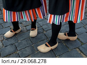 Девушка традиционной голландской одежде и деревянных башмаках (кломпах) стоит на булыжной мостовой (2018 год). Стоковое фото, фотограф Николай Винокуров / Фотобанк Лори