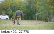 Man in a protective and trained dog walks away from the camera. Стоковое видео, видеограф Константин Шишкин / Фотобанк Лори