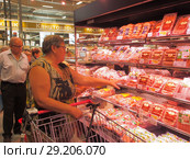 Женщина выбирает колбасную продукцию в торговом зале супермаркета Selgros Cash & Carry в Зеленограде в день открытия (2018 год). Редакционное фото, фотограф Сайганов Александр / Фотобанк Лори