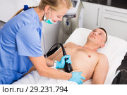 Woman doctor is doing vacuum massage procedure on belly of adult client. Стоковое фото, фотограф Яков Филимонов / Фотобанк Лори
