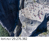 Вид на скалу Проповедника (Preikestolen) и людей, сидящих на краю. Туристическая природная достопримечательность. Норвегия (2018 год). Стоковое фото, фотограф Кекяляйнен Андрей / Фотобанк Лори