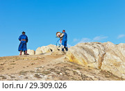 Baikal Lake. Olkhon Island. Shamans in traditional robes with colored ribbons and a tambourine conduct a rite and prayer at Cape Burkhan and bring gifts to local deities (2018 год). Редакционное фото, фотограф Виктория Катьянова / Фотобанк Лори