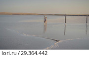 Slim sexy girl enjoying sunset, walks between wooden salt pillars of a salt lake. Стоковое видео, видеограф Ирина Мойсеева / Фотобанк Лори