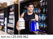 Athletic man seller demostration sport nutrition products in shop. Стоковое фото, фотограф Яков Филимонов / Фотобанк Лори