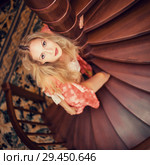 girl in silk robe stand on wooden spiral staircase. Стоковое фото, фотограф katalinks / Фотобанк Лори