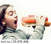 Hungry girl with open mouth and with giant bread and sausage sandwich on white background. Стоковое фото, фотограф Элина Гаревская / Фотобанк Лори