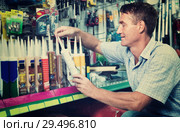 Portrait of male customer selecting sealant bottle i. Стоковое фото, фотограф Яков Филимонов / Фотобанк Лори