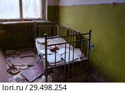 Спальное помещение в заброшенном детском саду в уничтоженном селе Копачи, 10-километровая зона отчуждения ЧАЭС, Украина (2018 год). Стоковое фото, фотограф Ольга Коцюба / Фотобанк Лори