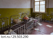 Спальное помещение в заброшенном детском саде в уничтоженном селе Копачи, 10-километровая зона отчуждения Чернобыльской АЭС, Украина (2018 год). Стоковое фото, фотограф Ольга Коцюба / Фотобанк Лори