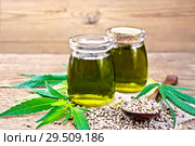 Масло конопляное в двух банках и ложка на доске. Стоковое фото, фотограф Резеда Костылева / Фотобанк Лори