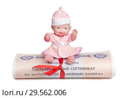 Пупс сидит сверху на государственном материнском капитале, свернутым в свиток с красной лентой. Стоковое фото, фотограф Элина Гаревская / Фотобанк Лори