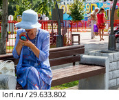 Пенсионерка красит губы на скамейке городского парка "Арена" города Воронеж (2018 год). Редакционное фото, фотограф Вячеслав Палес / Фотобанк Лори