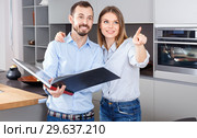 Young beautiful couple standing with book in modern kitchen inte. Стоковое фото, фотограф Яков Филимонов / Фотобанк Лори