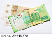 Российские деньги. Купюры номиналом 200 и 100 рублей на белом фоне. Стоковое фото, фотограф Елена Коромыслова / Фотобанк Лори