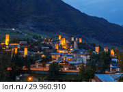 Mestia at dusk, illuminated Svan towers on the background of a mountain slope, Upper Svaneti, Georgia (2018 год). Стоковое фото, фотограф Юлия Бабкина / Фотобанк Лори