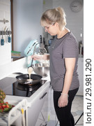 Young woman making pancakes on the kitchen. Стоковое фото, фотограф Константин Шишкин / Фотобанк Лори