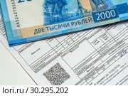 Коммунальный платежи за водоснабжение и водоотведение. Квитанция на оплату коммунальных услуг за воду и 2000 рублей (2019 год). Редакционное фото, фотограф Игорь Низов / Фотобанк Лори