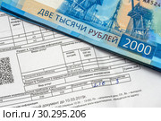 Коммунальный платежи за водоснабжение и водоотведение. Квитанция на оплату коммунальных услуг за воду и двухтысячные банкноты. Стоковое фото, фотограф Игорь Низов / Фотобанк Лори