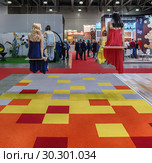 Москва, 12 марта 2019 года. Выставка Batimat в выставочном комплексе "Крокус Экспо". Манекены сидят на качелях над ярким полом в павильоне Tarkett. Редакционное фото, фотограф Светлана Васильева / Фотобанк Лори